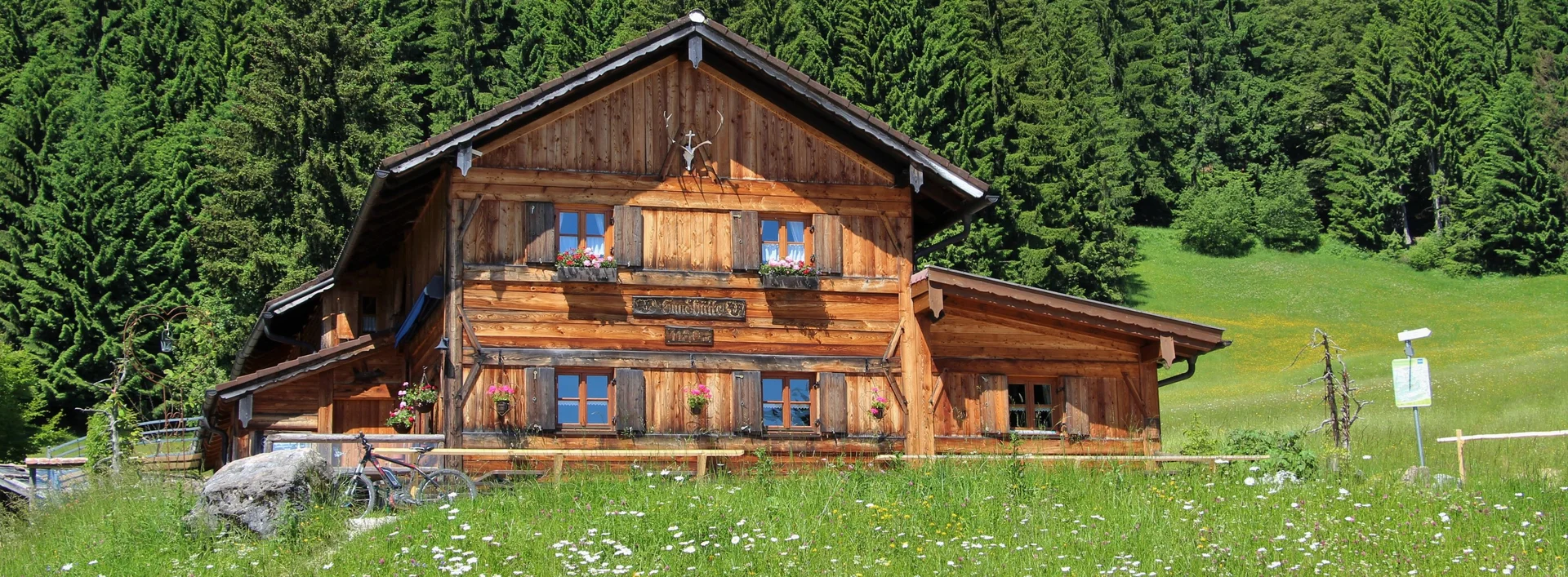 Sommerliche Sicht auf grüne Wiesen und die Edelsberghütte in Pfronten.