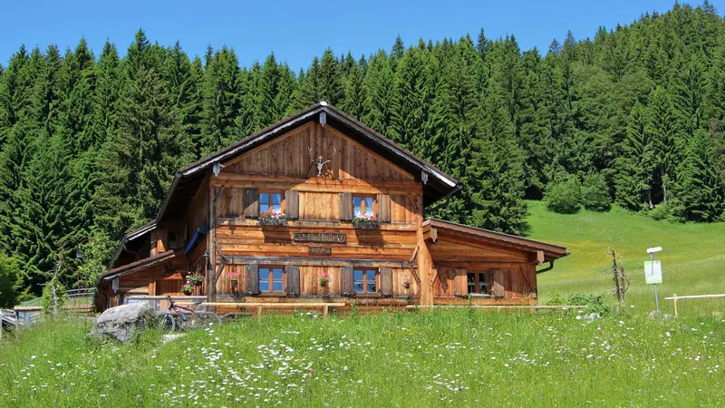 Sommerliche Sicht auf grüne Wiesen und die Edelsberghütte in Pfronten.