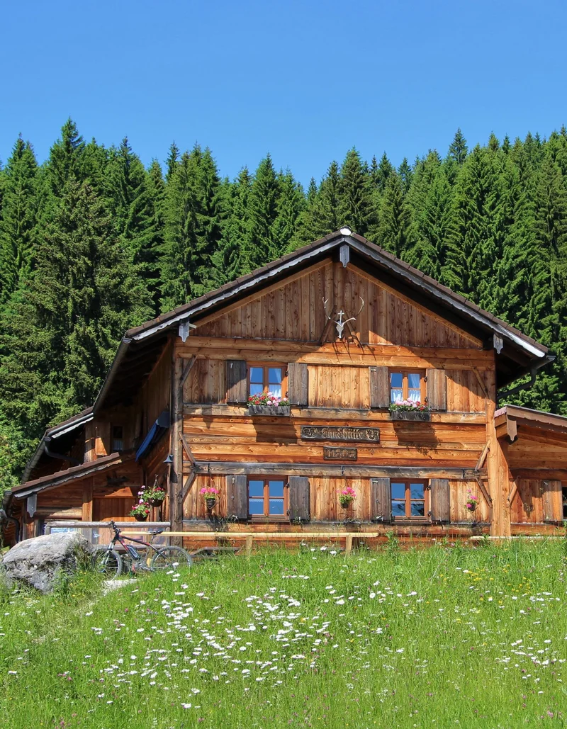 Sommerliche Sicht auf grüne Wiesen und die Edelsberghütte in Pfronten.