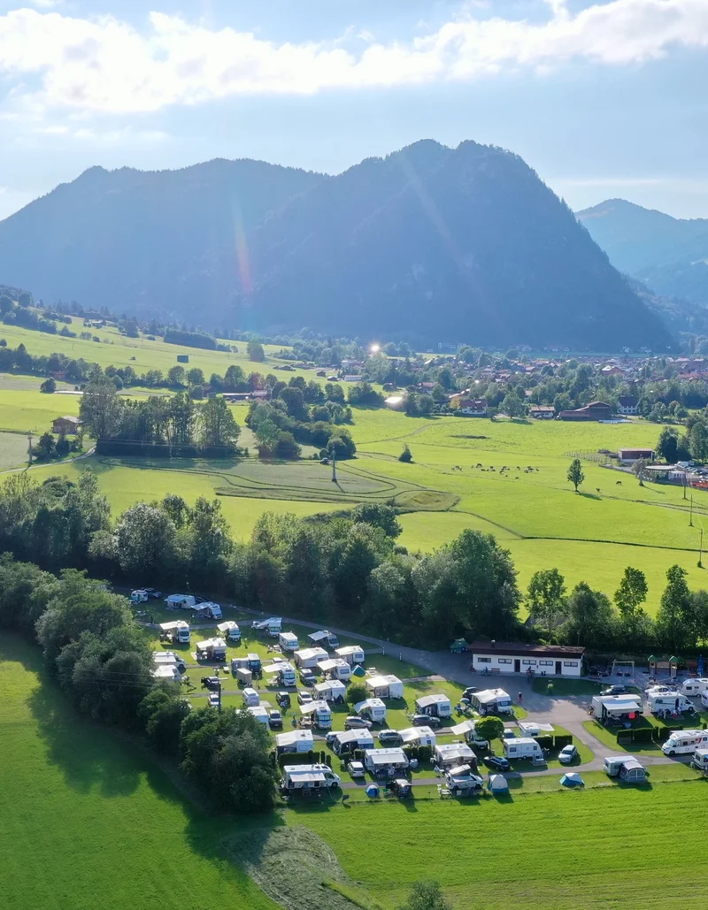 Sonniger Blick von oben auf den Campingplatz in Pfronten mit weitem Panoramablick.