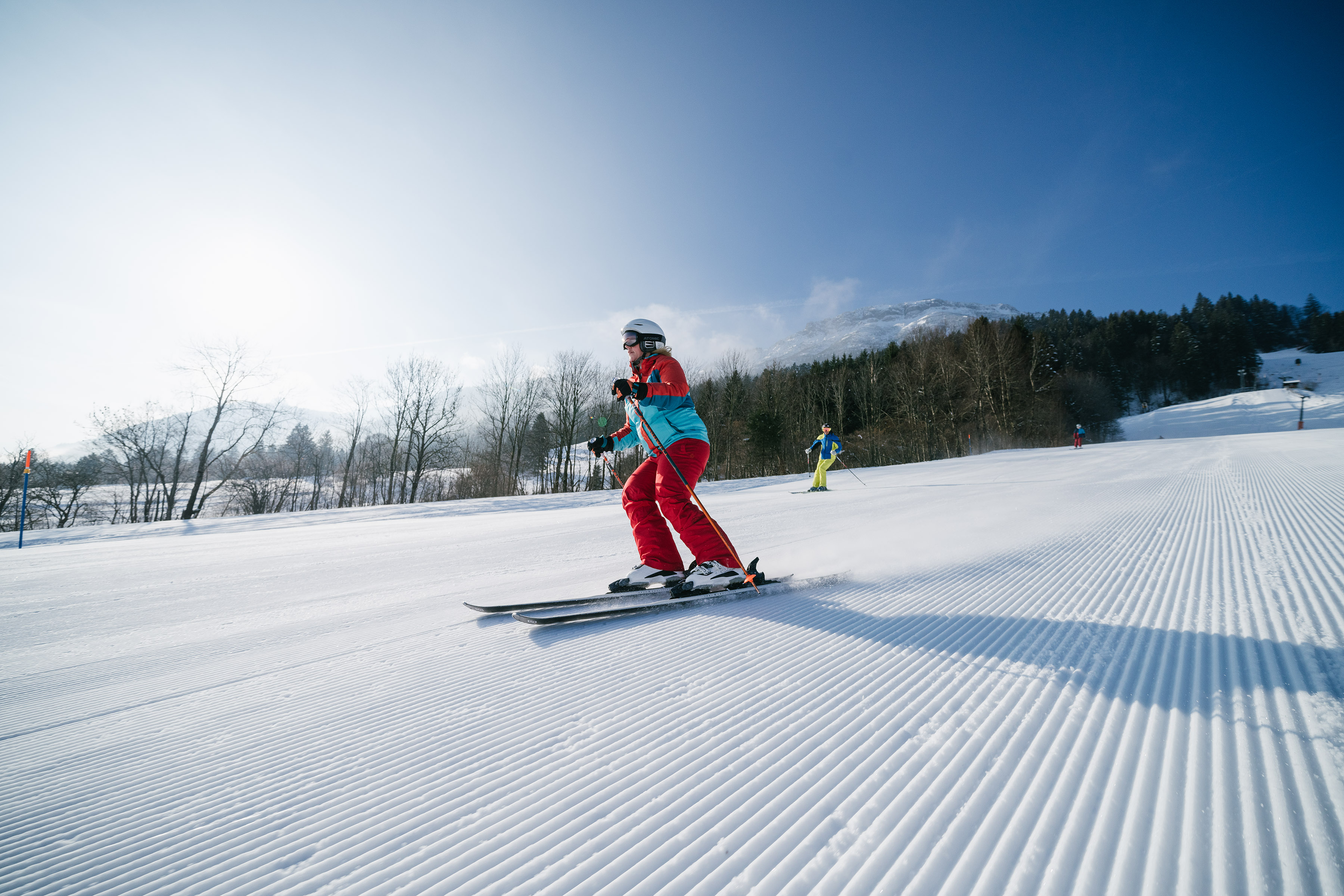 Skifahrer auf der Piste, im Hintergrund eine verschneite Landschaft.