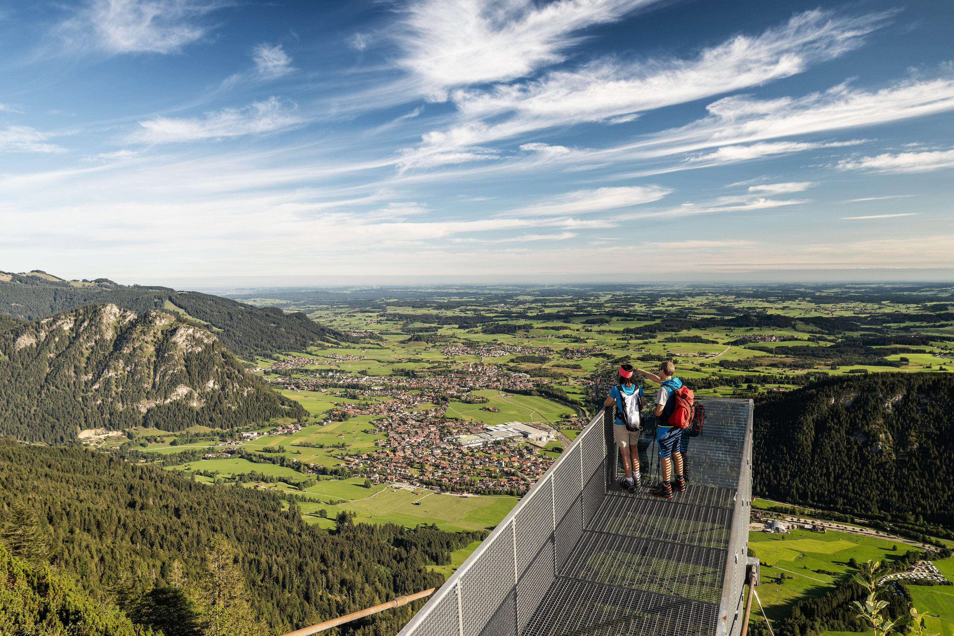 Weitreichender Blick über den Aussichtssteg auf dem Breitenberg auf das Pfrontener Tal und die umliegende Berglandschaft.