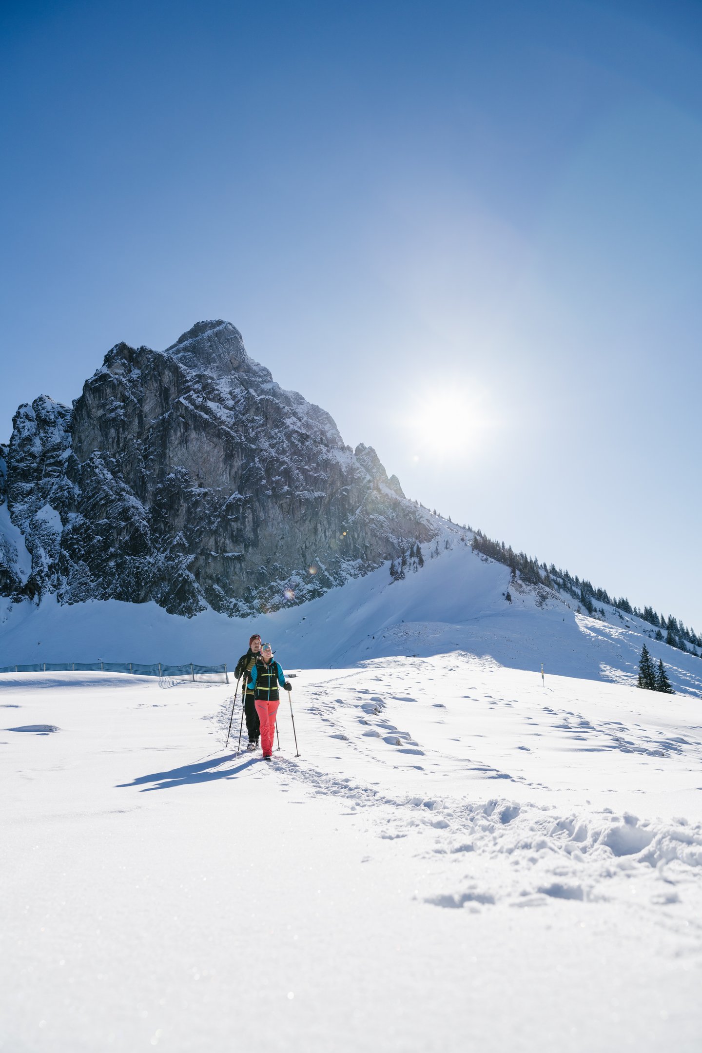 Wanderer auf verschneiten Wegen mit einem winterlichen Bergpanorama.